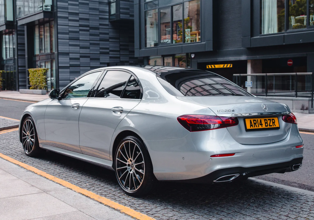 Silver Mercedes E-Class positioned for an executive airport transfer service in an urban setting.