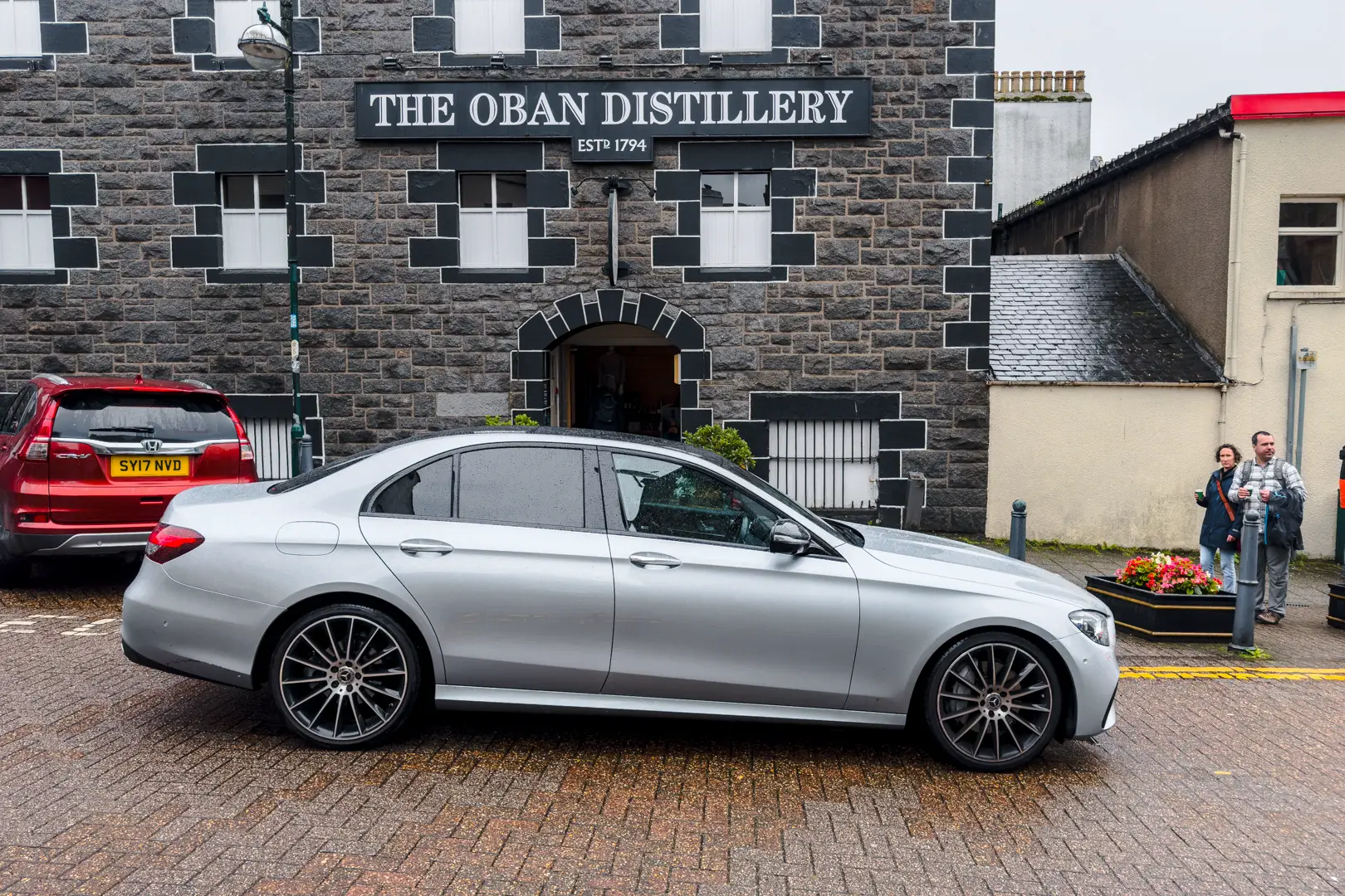 Edinburgh to St Andrews Transfer - Mercedes E-Class at Oban Distillery. Silver Mercedes E-Class awaiting passengers for their travel to St Andrews outside Oban Distillery.