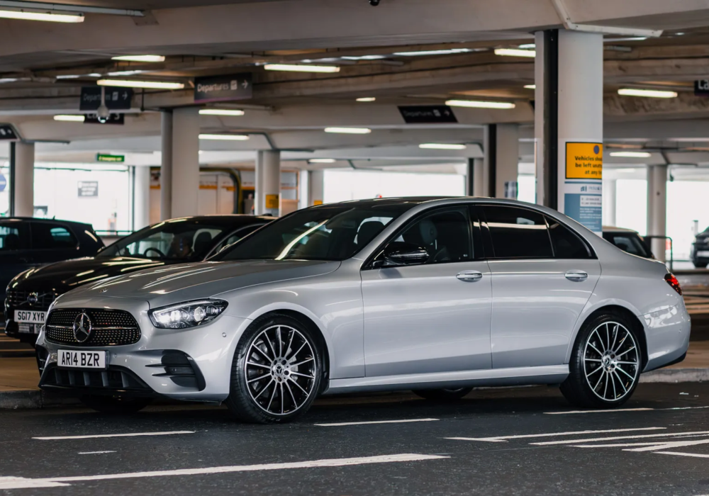 Silver Mercedes E-Class ready for executive airport pickup at Edinburgh Airport's drop-off area.