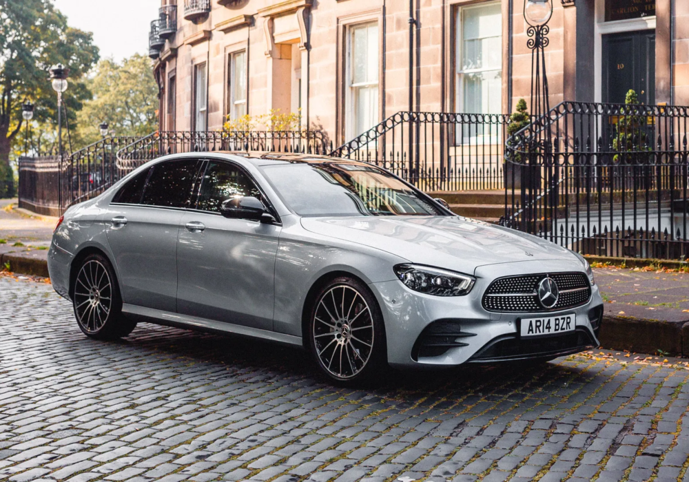 Silver Mercedes-Benz E-Class parked on an Edinburgh street, blending modern luxury with historical charm.