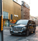 Executive transfer service with a black Mercedes V-Class van near Scott Monument in Edinburgh, catering to hotel and airport routes.