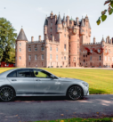 A silver Mercedes-Benz E-Class parked in front of the historic Glamis Castle in Scotland, symbolising executive travel in a land of heritage.