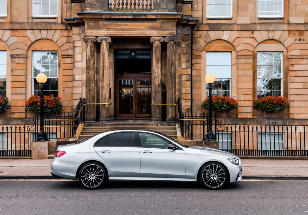 Silver Mercedes E-Class ready for executive transfers, parked outside a Glasgow hotel.
