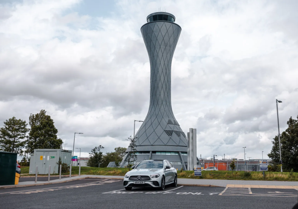 Silver Mercedes E-Class in front of the unique Edinburgh Airport Control Tower.