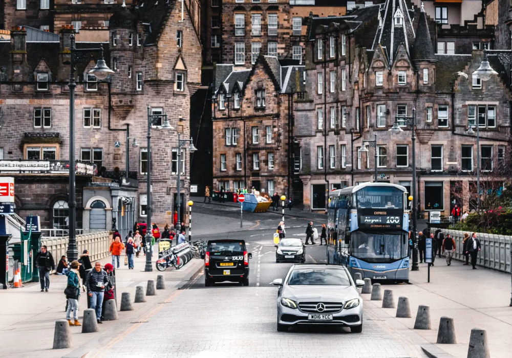 Edinburgh Executive Transfers - Silver Mercedes-Benz E-Class Amidst City Life Silver Mercedes-Benz E-Class on an Edinburgh street, showcasing executive transfer services in the heart of the city.