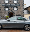 Grey Mercedes-Benz E-Class parked in front of the Oban Distillery, ready to enhance any travel experience in Scotland.