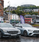 Two Mercedes E-Class sedans parked in Oban, ready for executive transfer services, with the town's charm in the backdrop.